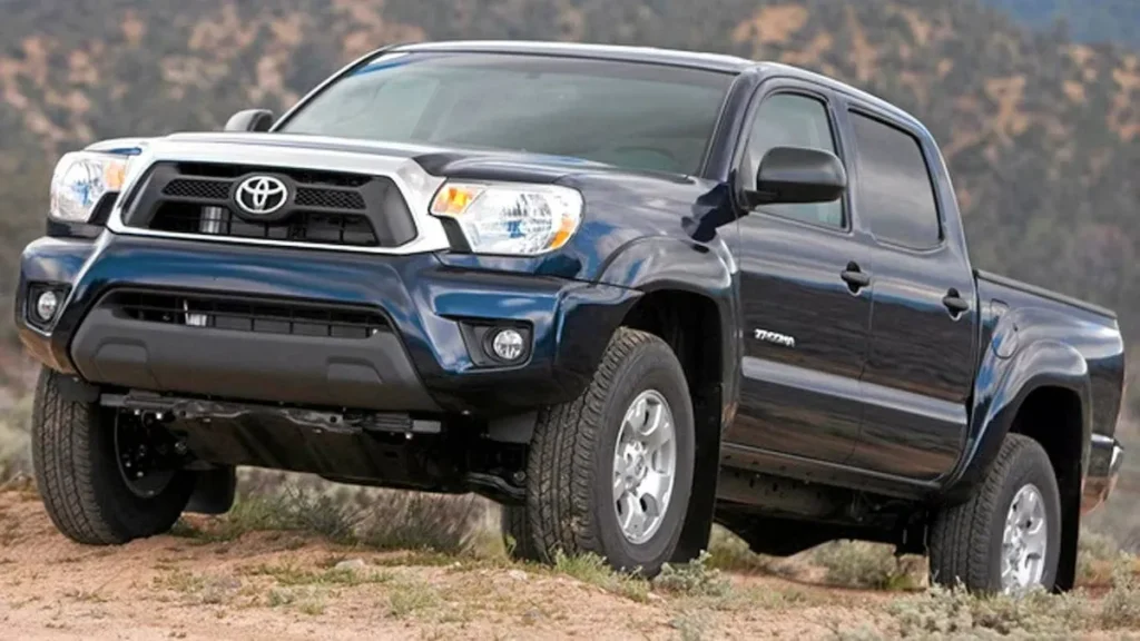 A dark blue 2012 Toyota Tacoma Double Cab, representing one of the most popular model years from the Toyota Tacoma years of the second generation (2012-2015 facelift), parked on a dirt trail.