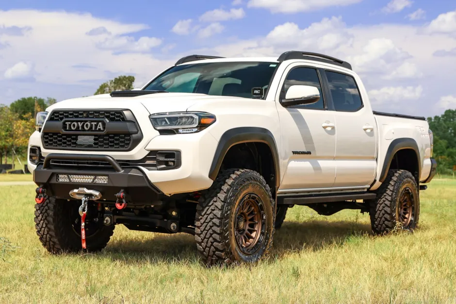 White 2022 Toyota Tacoma 4x4 with lift kit and bronze alloy wheels, an iconic off-road build from the recent Toyota Tacoma years.