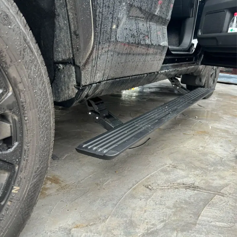Detailed shot of the Toyota FJ power running boards lowered below the door sill on a dusty vehicle, showing the robust electric motor arms and side step.