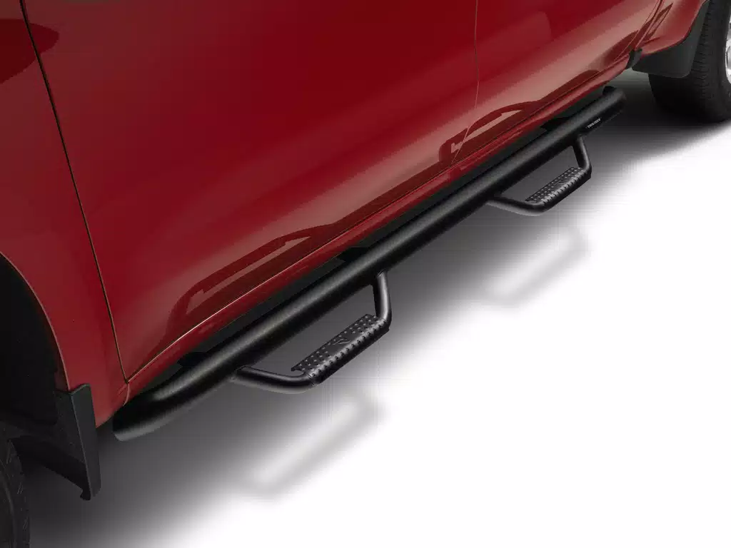 Black tubular side steps with two textured drop steps installed on a red pickup truck for easy cabin access.