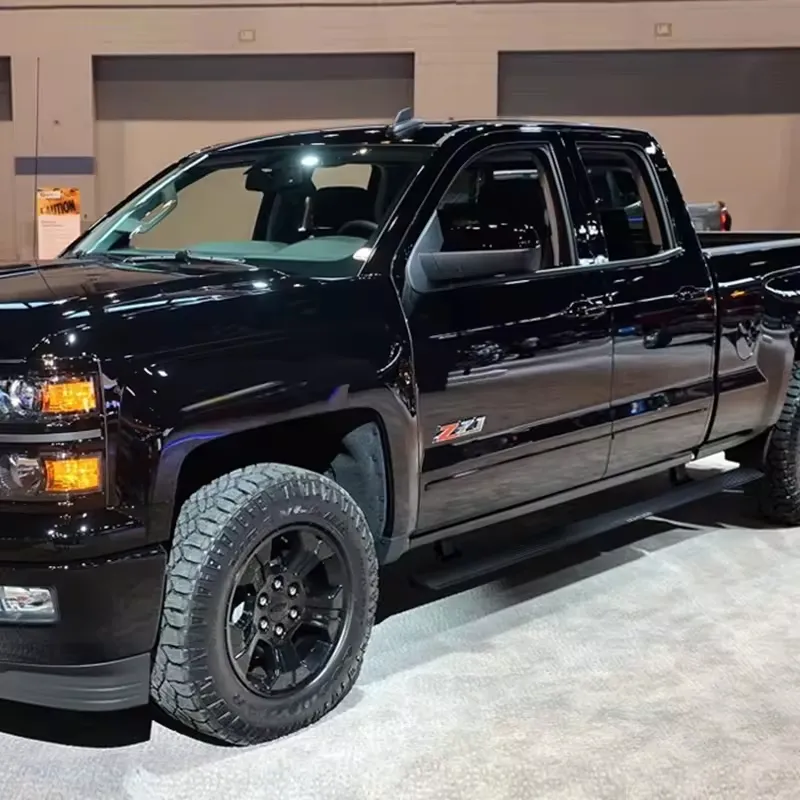 A custom black Chevy Silverado 1500 displayed at an auto show, featuring durable black running boards and off-road tires.