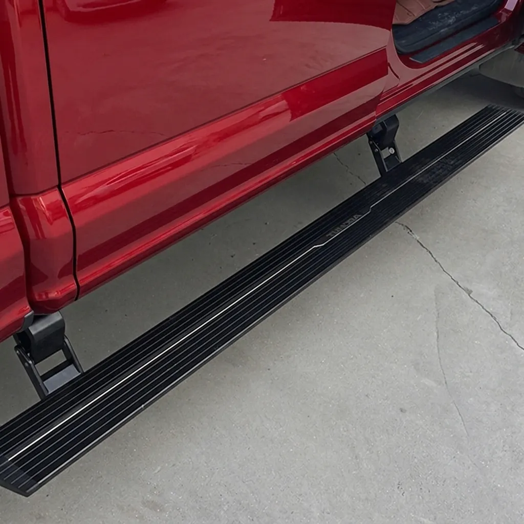 Close-up view of the textured step surface and linkage of f150 running boards on a red vehicle.