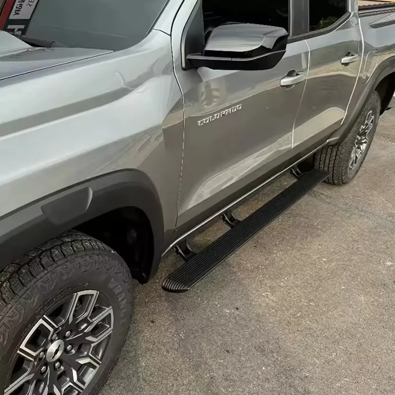 Detailed close-up shot of black chevy colorado running boards on a silver truck, showing texture and brackets.