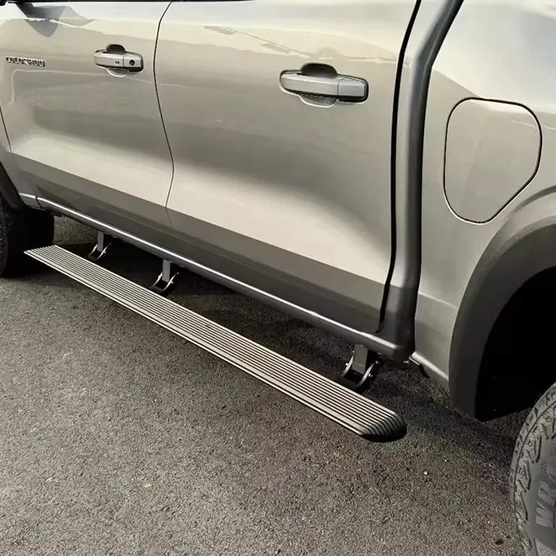 A silver Chevy Colorado truck with its power running boards fully deployed, showing the mechanism and step surface.