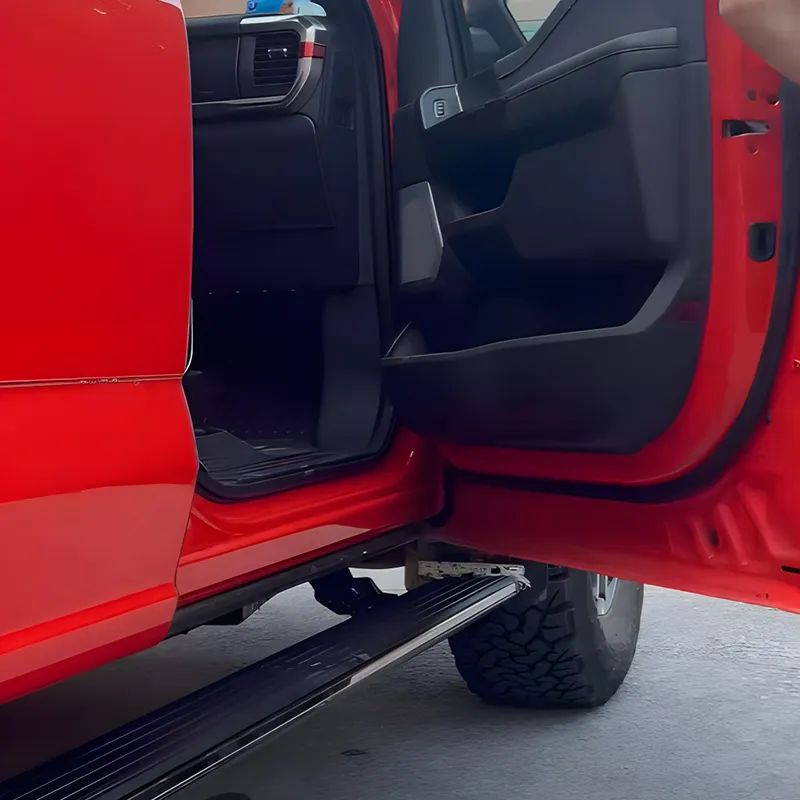 Open door perspective showing the integration and deployment of f150 running boards on a red truck.