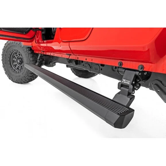 Rough Country Electric Running Boards fully deployed on a red off-road Jeep, showing the black grooved side step and heavy-duty power-retractable mounting bracket.