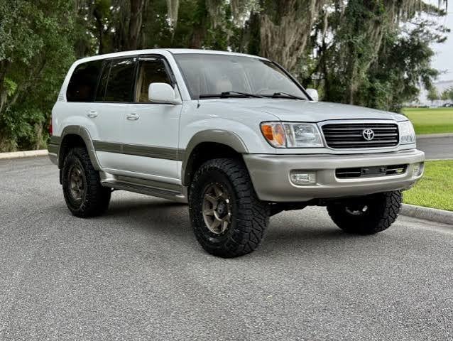 White Toyota Land Cruiser 100 Series (LC100) parked on a road, representing a Power Running Boards Manufacturer.