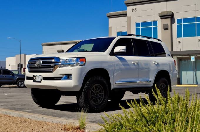 White Toyota Land Cruiser 200 Series (LC200) parked in front of a building, representing a Retractable Running Boards Manufacturer.