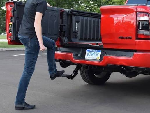 Heavy-duty foldable tailgate step on a red truck, a practical choice among the best truck accessories for safe and easy rear bed access.