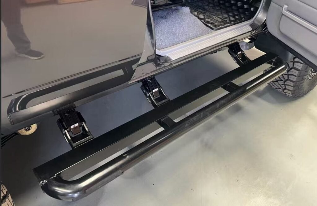 Close-up of a black tubular stainless steel power running board extended from a pickup truck, showcasing the durable Power Running Board Materials and motorized hinge mechanism.
