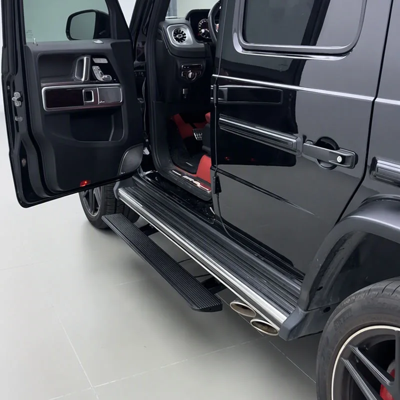 Black Mercedes-Benz G500 with the door open, showcasing the fully extended Mercedes-Benz G500 Electric Running Boards, a red leather interior, and side exhaust pipes.