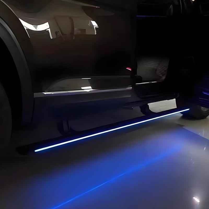 Nighttime view of an extended Mercedes-Benz V-Class Electric Running Board casting a vibrant blue light onto the ground beneath the vehicle.
