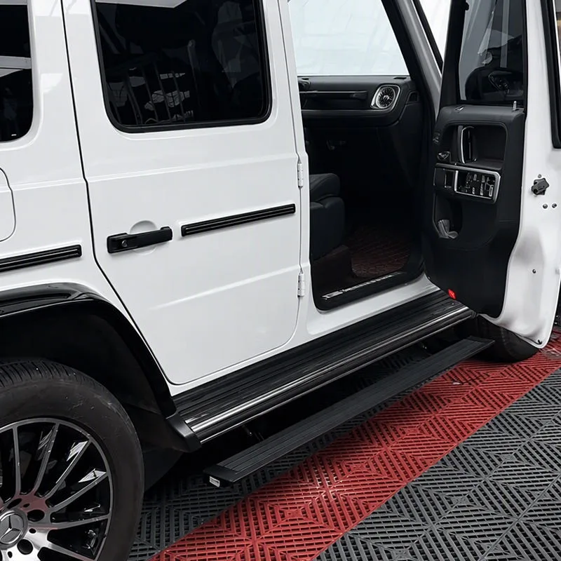 White Mercedes-Benz G550 with the front door open, revealing the extended Mercedes-Benz G550 Electric Running Boards and a glimpse of the black interior.