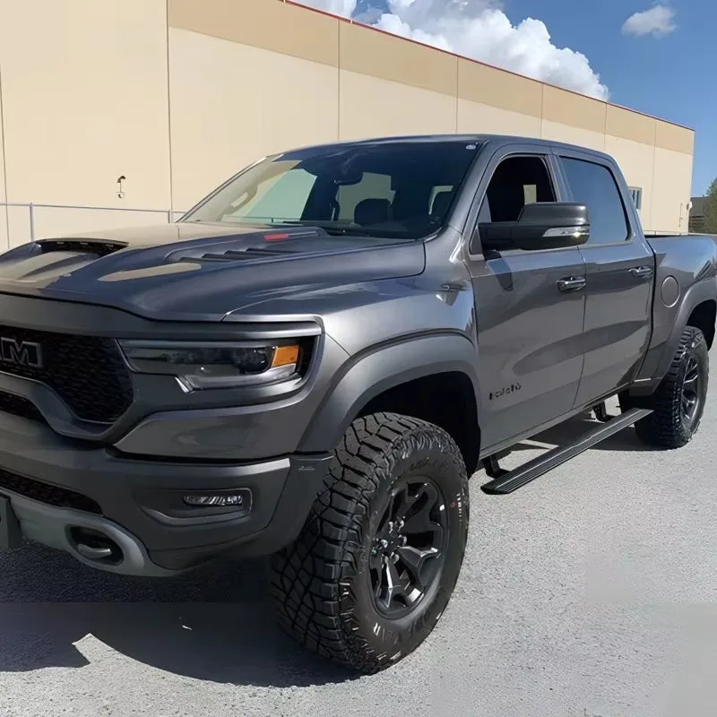 Gray Ram 1500 TRX parked outdoors featuring retracted power running boards and aggressive off-road tires, showcasing a clean side profile.