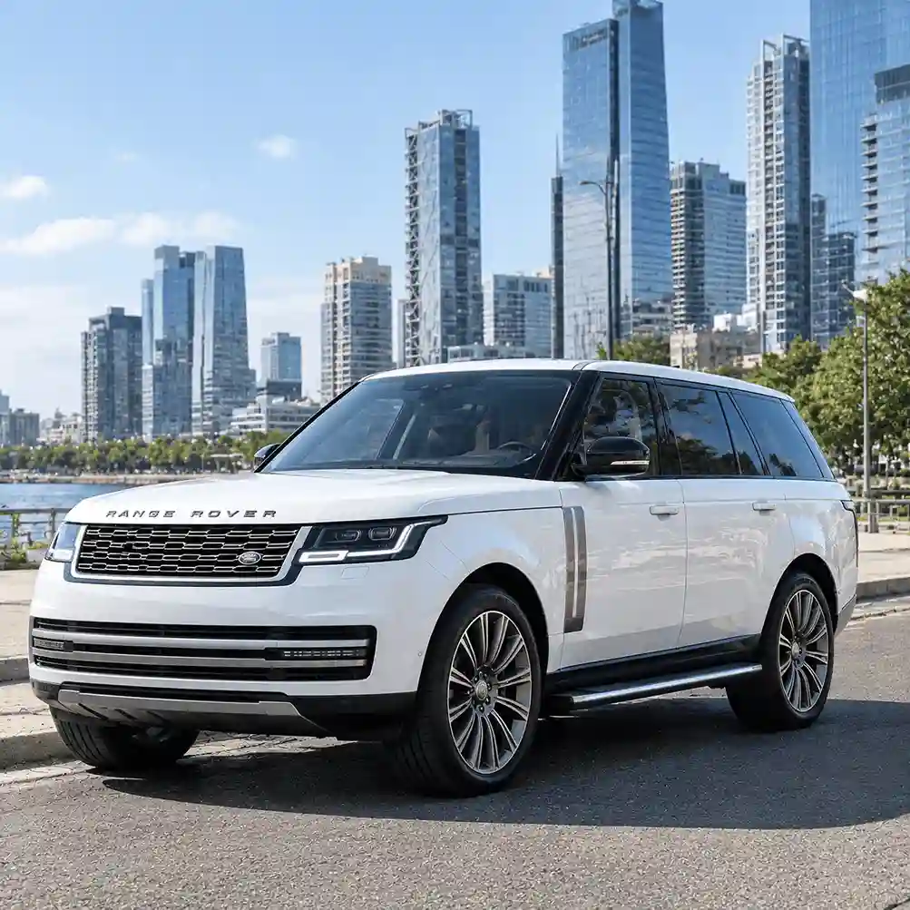 A white Range Rover luxury SUV parked on a city street with a modern skyline in the background. This image highlights the vehicle's elegant design and is ideal for showcasing compatible accessories like range rover power running boards for convenient urban access.
