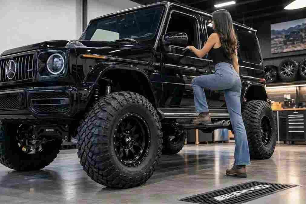 A woman stepping into a lifted black Mercedes-AMG G-Wagon equipped with mercedes-benz-electric-running-boards in a garage.