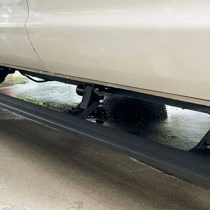 Close-up view of fully deployed Hilux power running boards and heavy-duty mounting brackets over a wet concrete surface.