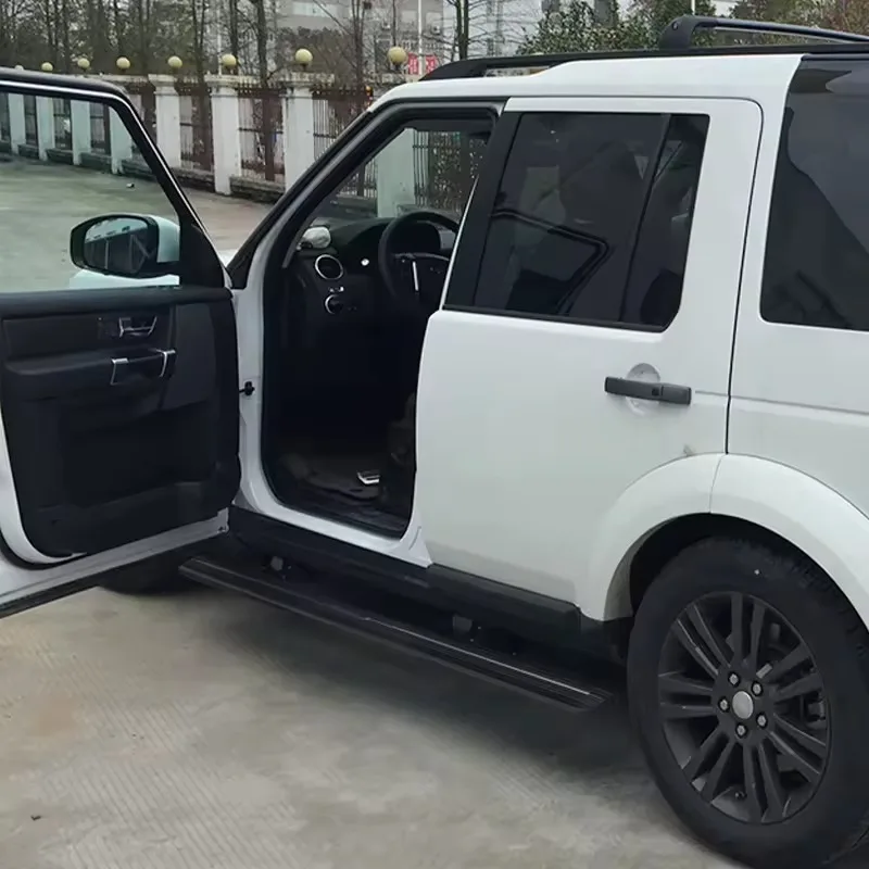 Open front door of a white Land Rover Discovery 4 Electric Side Steps deployed outdoors, showing the interior and step access.