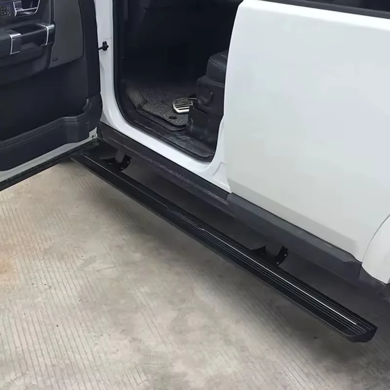Close-up of the deployed Land Rover Discovery 4 Electric Side Steps running board with textured black tread, seen through an open car door.
