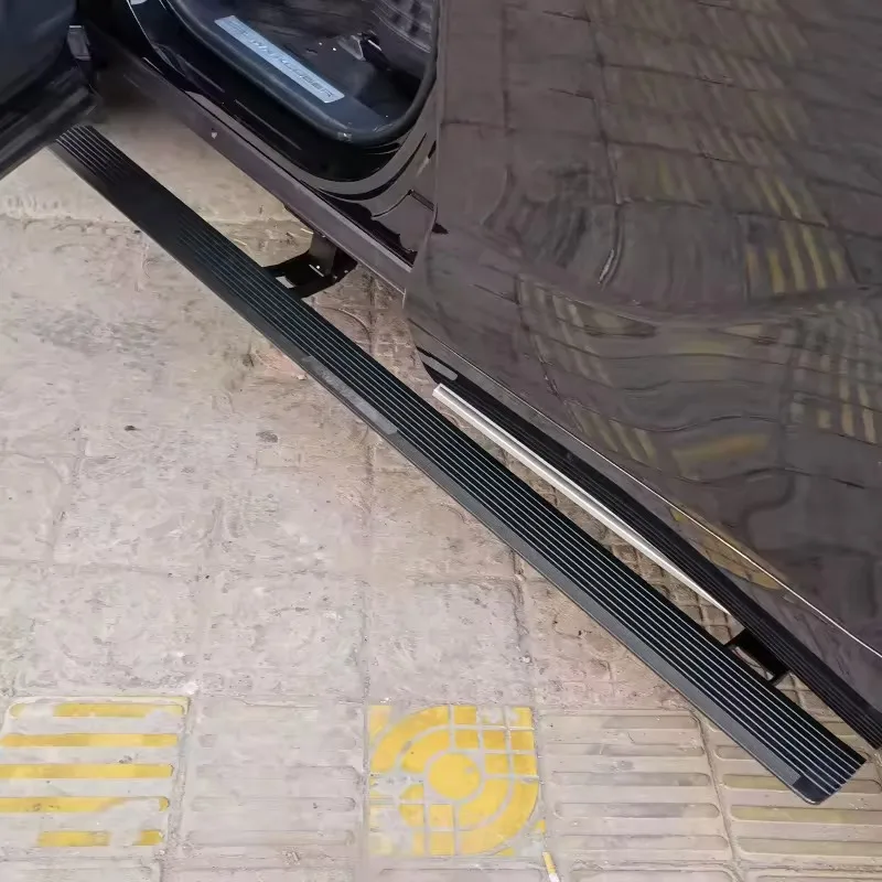 Black Land Rover Discovery 5 Electric Side Steps fully deployed over yellow tactile paving, captured through an open car door in an urban setting.