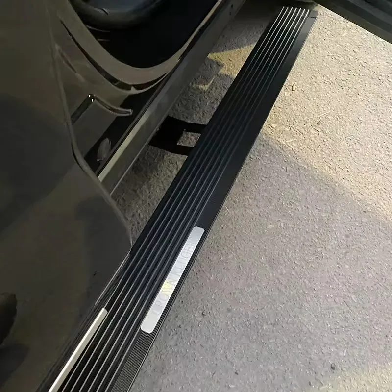 Close-up of a deployed Land Rover Discovery 5 Electric Side Steps running board on a black vehicle, highlighting the textured black tread and illuminated silver accent strip.