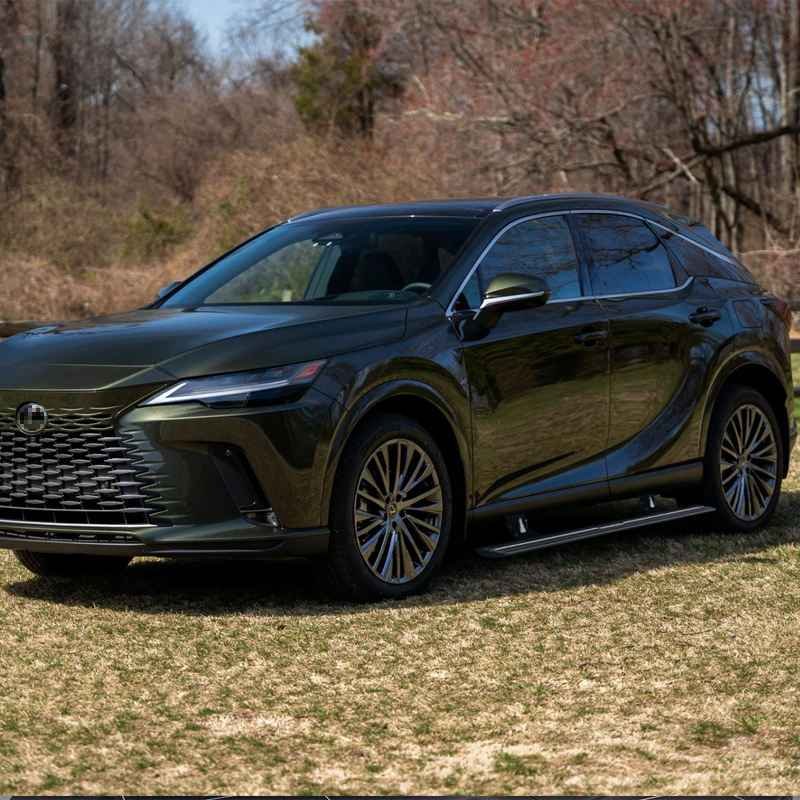 Side view of a dark green Lexus RX SUV in a natural setting equipped with lexus rx450h electric running boards.