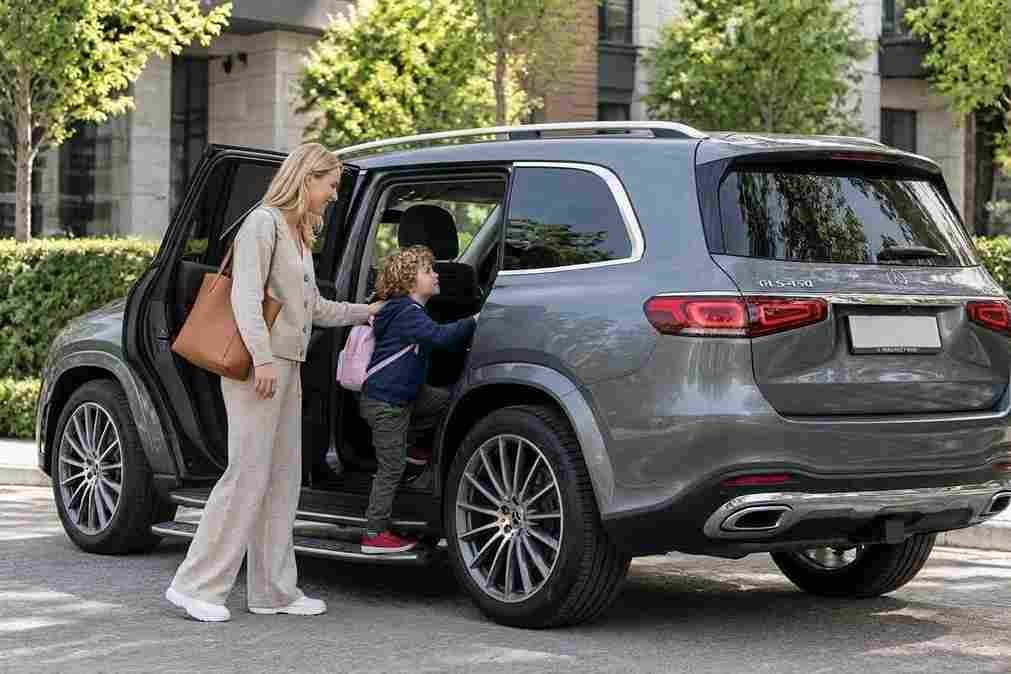 A child boarding a grey Mercedes-Benz GLS 450 using mercedes-benz-electric-running-boards, assisted by his mother.