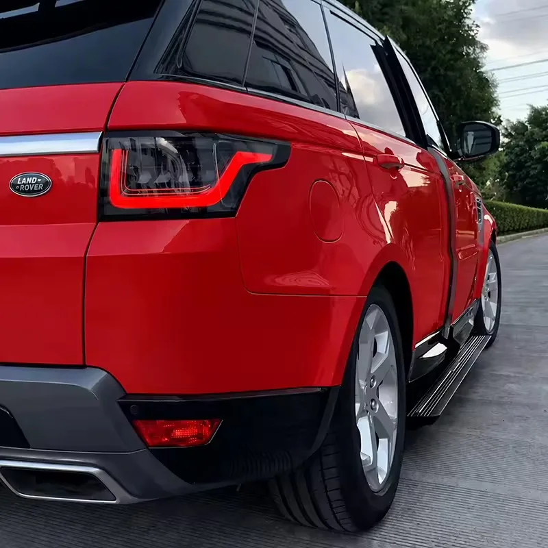 Outdoor rear quarter view of a red Range Rover Sport with the Range Rover Sport Electric Side Steps fully extended for easy access.